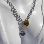 Stylish chunky stainless steel necklace featuring two heart charms combined with gold plated stainless steel